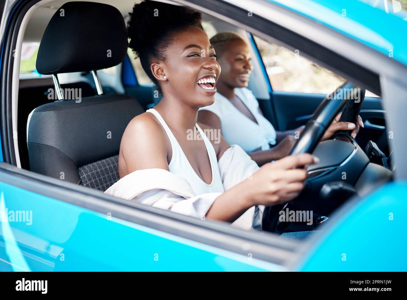 Woman driving, friends and roadtrip for a fun and happy drive while enjoying their vacation, trip and journey together. Black women laughing and talking while sitting in car for an adventure or lift Stock Photo