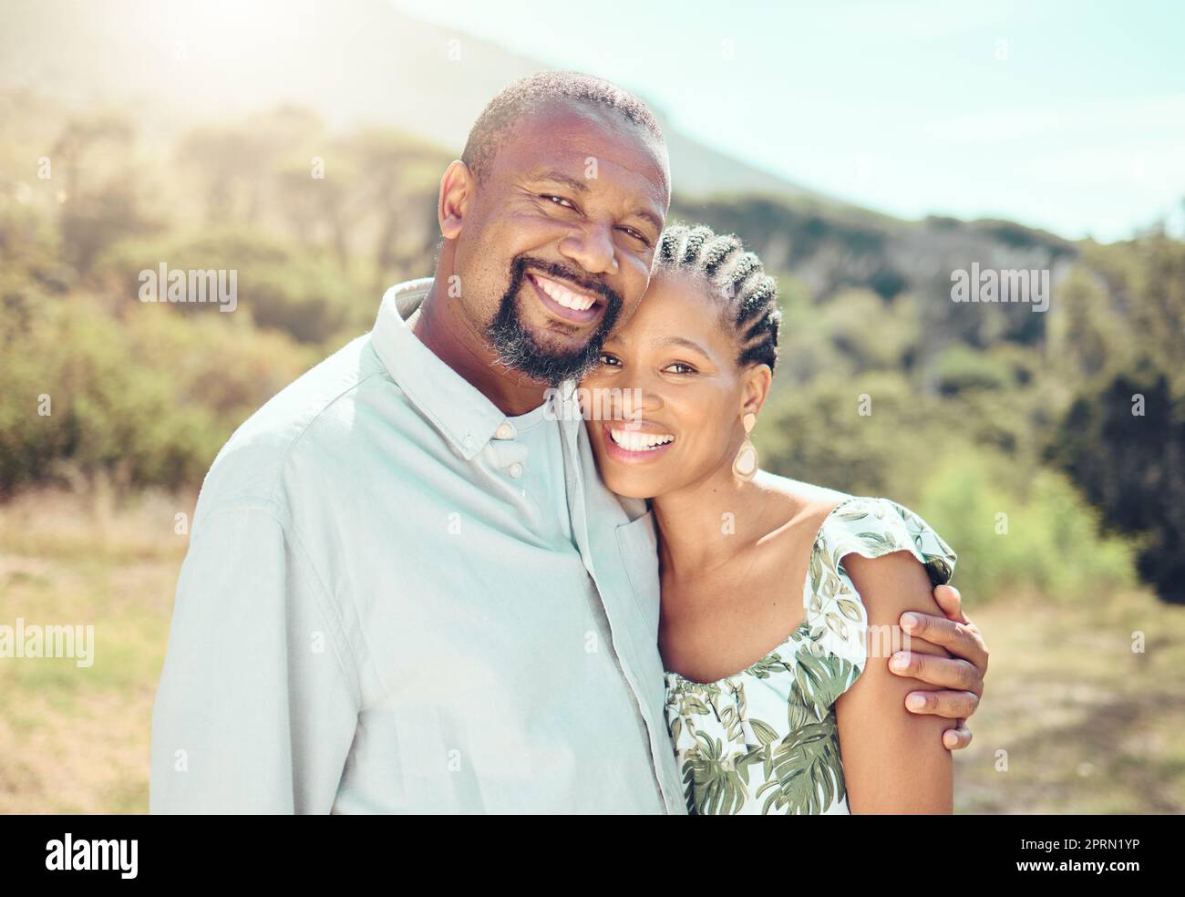 Happy, smile and love black couple relax in garden, park or nature together outdoors. Portrait african people, partner date and romance marriage in safe bonding, intimate hug and care relationship Stock Photo