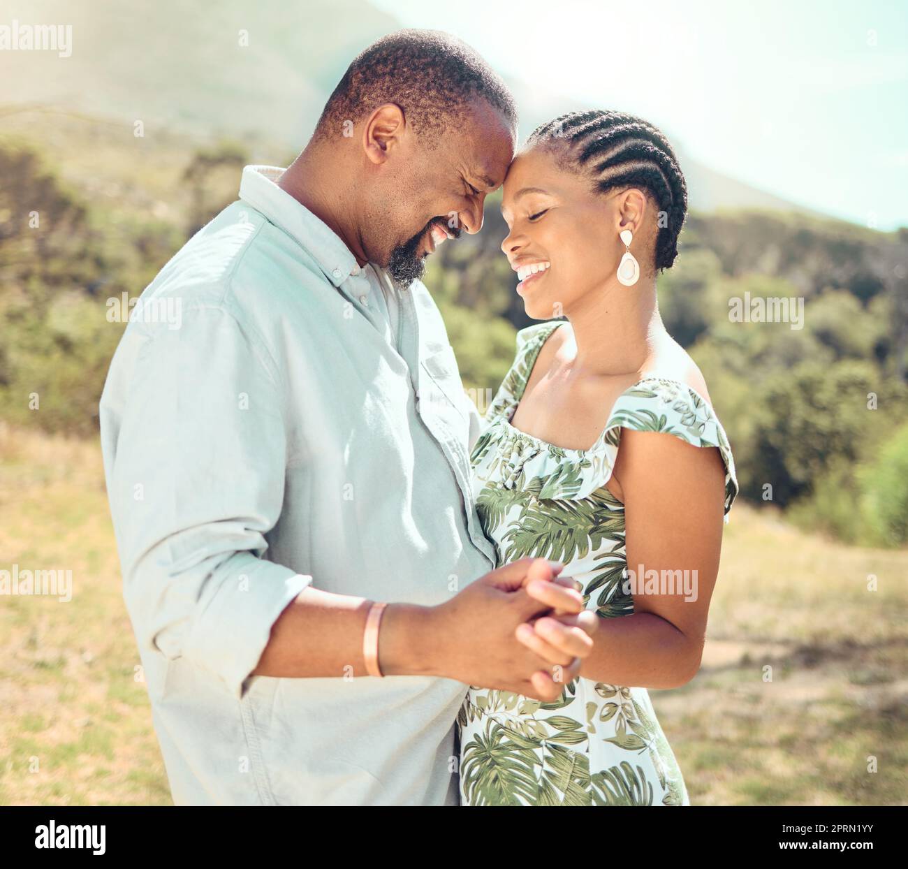 Black couple dancing in garden, park or nature together outdoors for love, relax and playful fun. African people, partners on a date and happy romantic marriage, intimate dance and care relationship Stock Photo