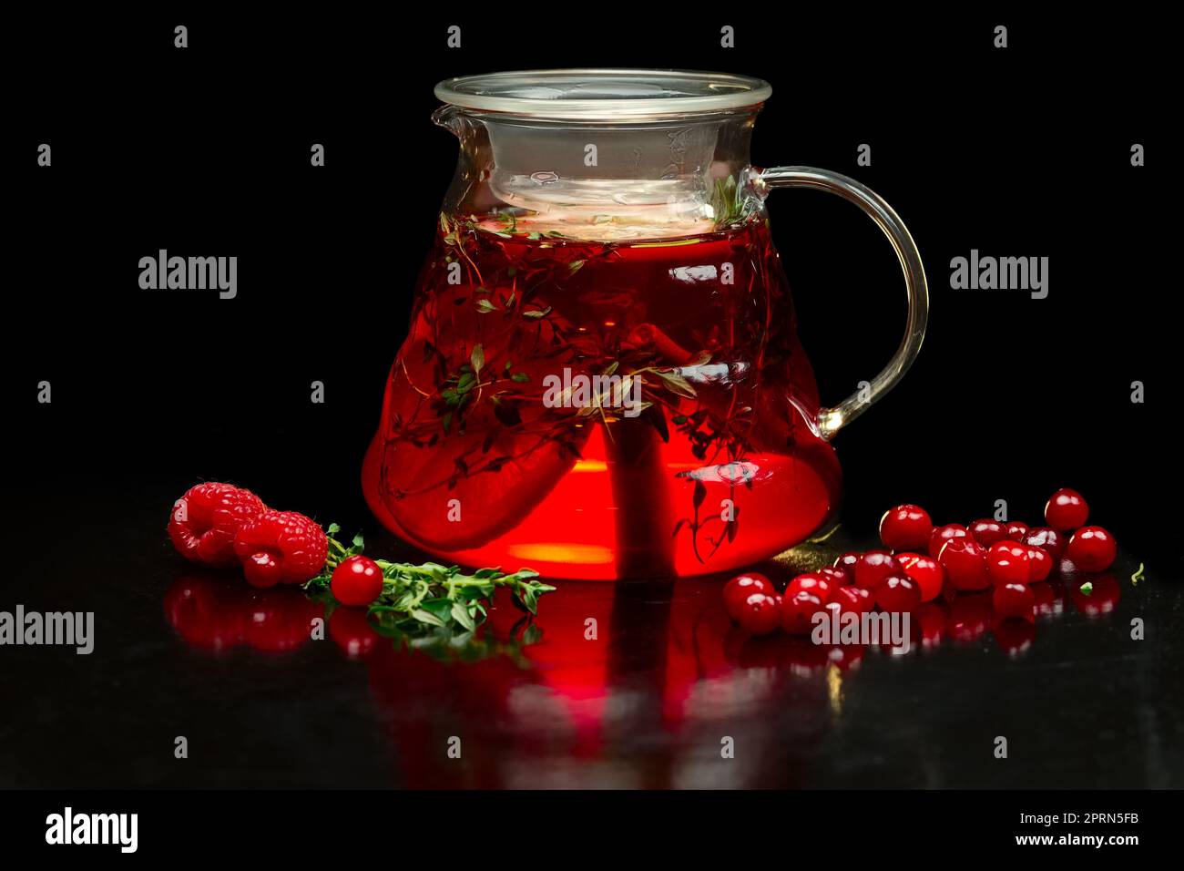 Berry tea with fresh currants, raspberries and strawberries. Teapot with fruits and berries. Stock Photo