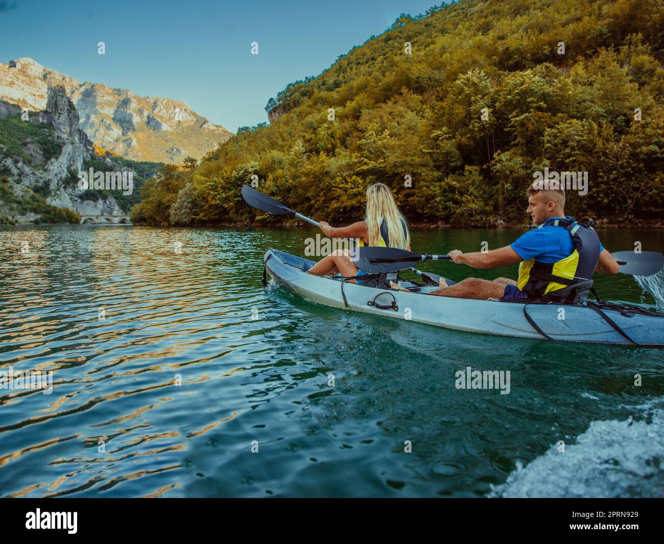 A young couple enjoying an idyllic kayak ride in the middle of a ...