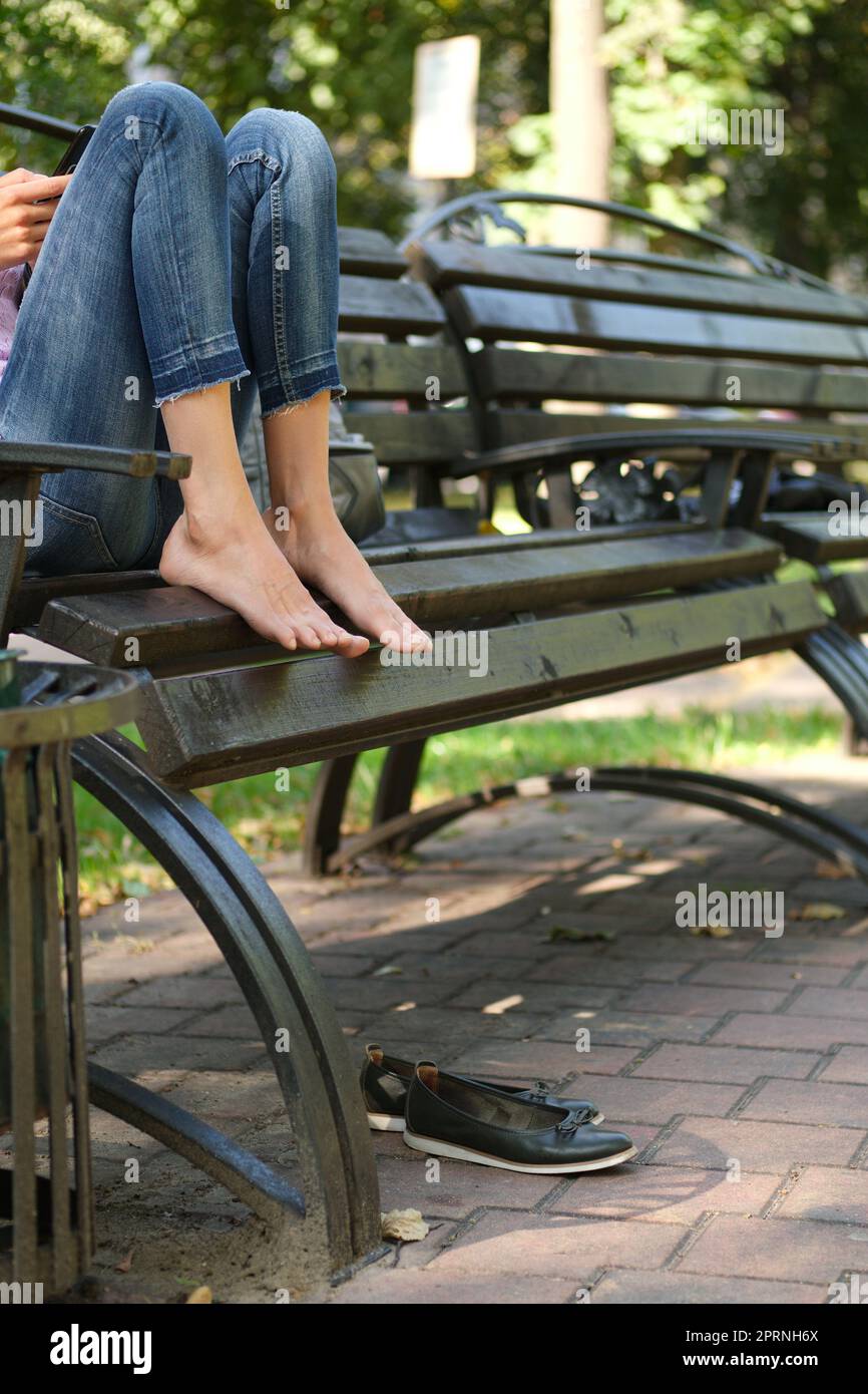 Sitting on the bench with feet. Tired bare feet on wooden settle and