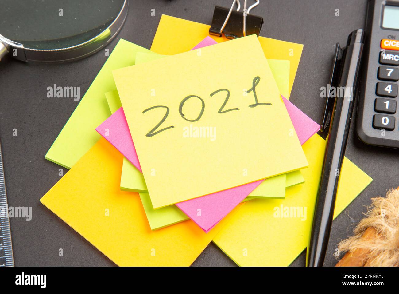 bottom close view written on sticky note colorful sticky notes lupa pen calculator on dark background Stock Photo