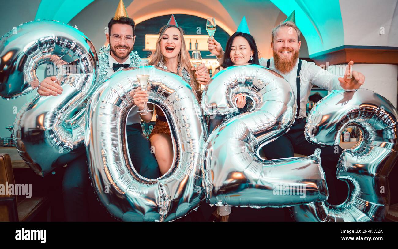 Group of party people celebrating the arrival of 2023, men and women looking into camera Stock Photo
