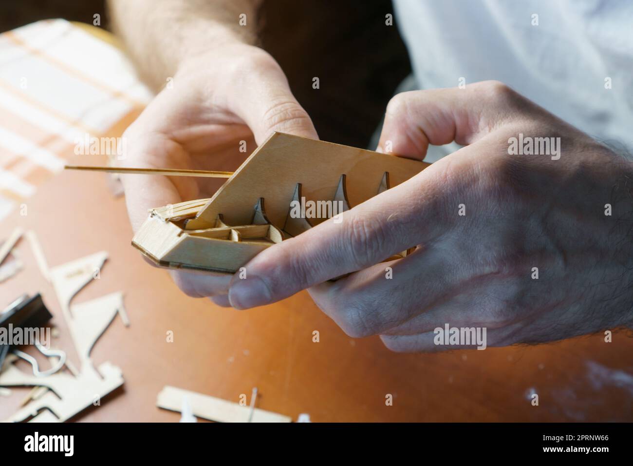 Hands of man gluing plywood details for ship model with glue, holding ...