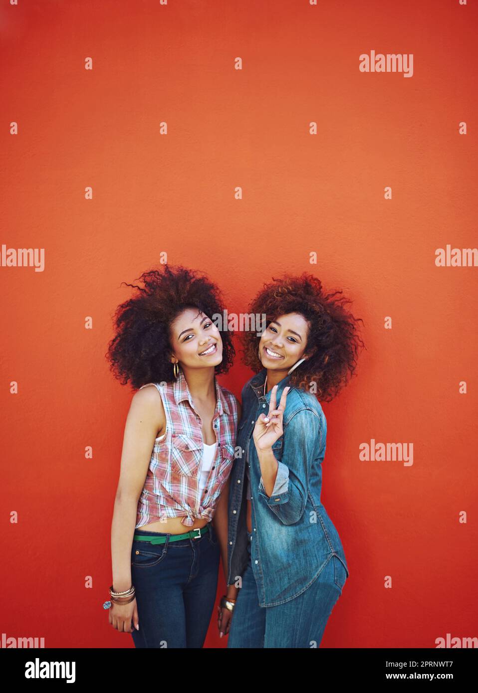 Best friendstwo personalities, one heart. two young friends posing against a red background. Stock Photo