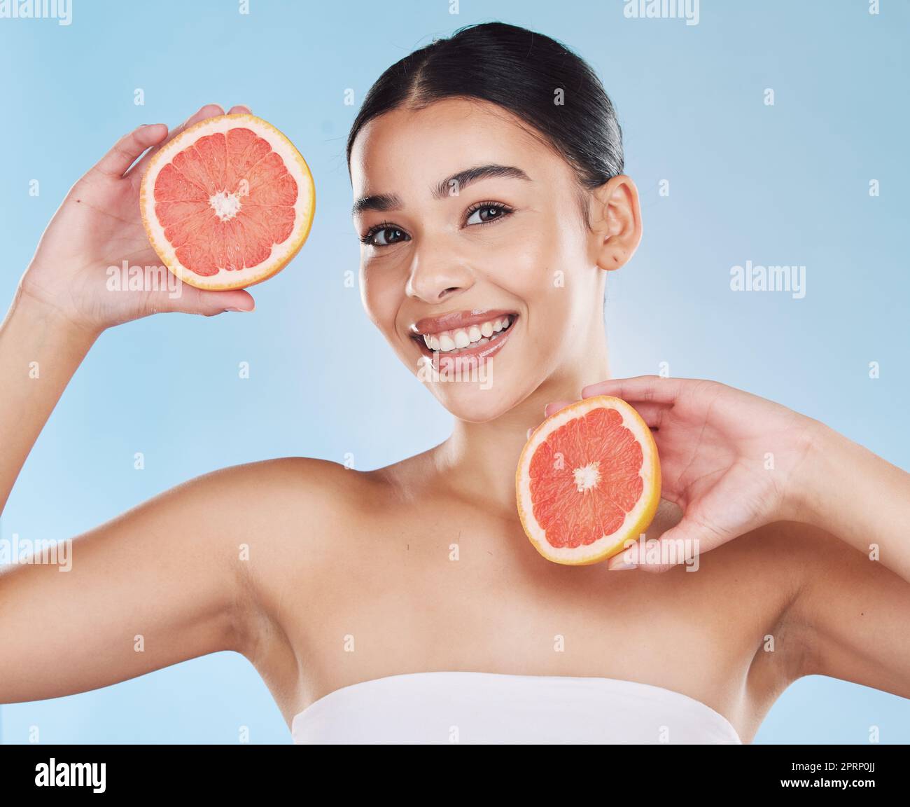 Grapefruit, skincare, face and diet wellness keeps her happy and healthy for skin healthcare, eat healthy fruit with nutrition. Portrait of a beauty woman in studio against a blue background Stock Photo