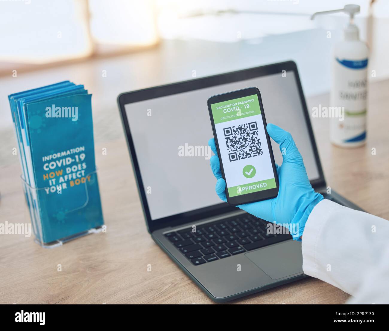 Covid, vaccine and passport on smartphone for travel, safety or security during virus pandemic. Laptop, hands and phone app with digital corona QR code for international, global and safe traveling. Stock Photo