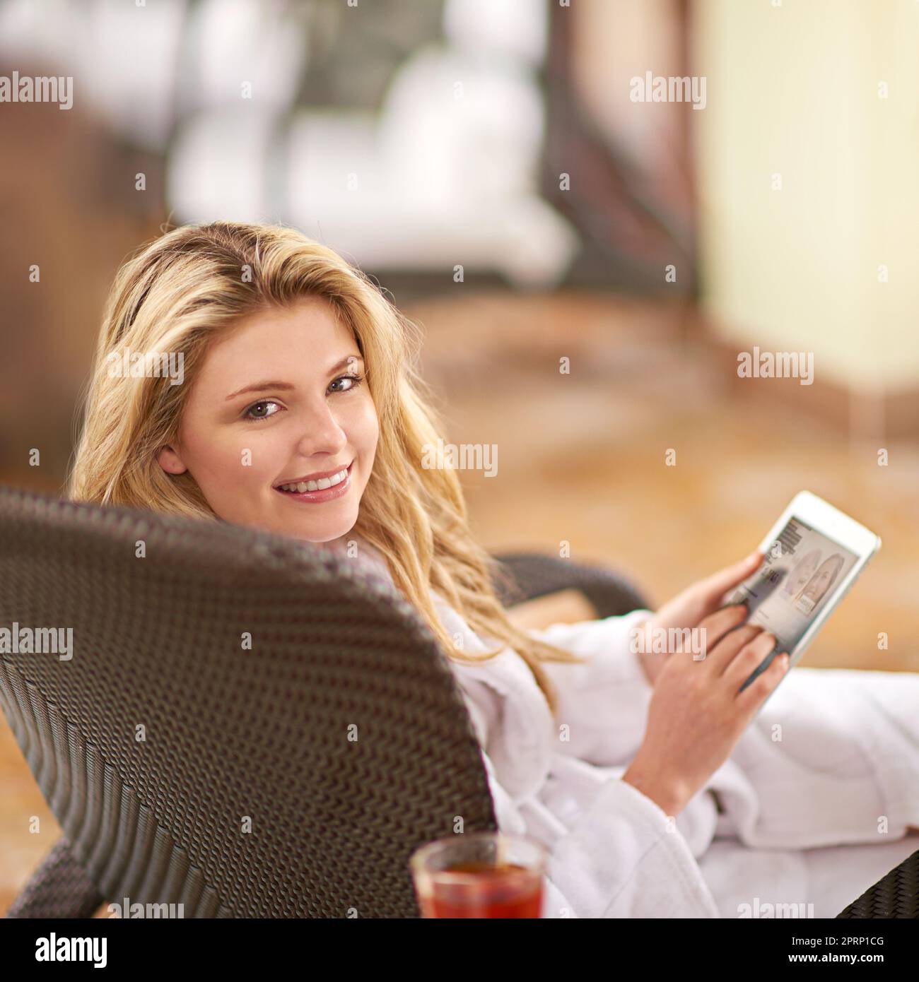 My friends are going to be so jealous. a young woman relaxing with her digital tablet at a day spa. Stock Photo
