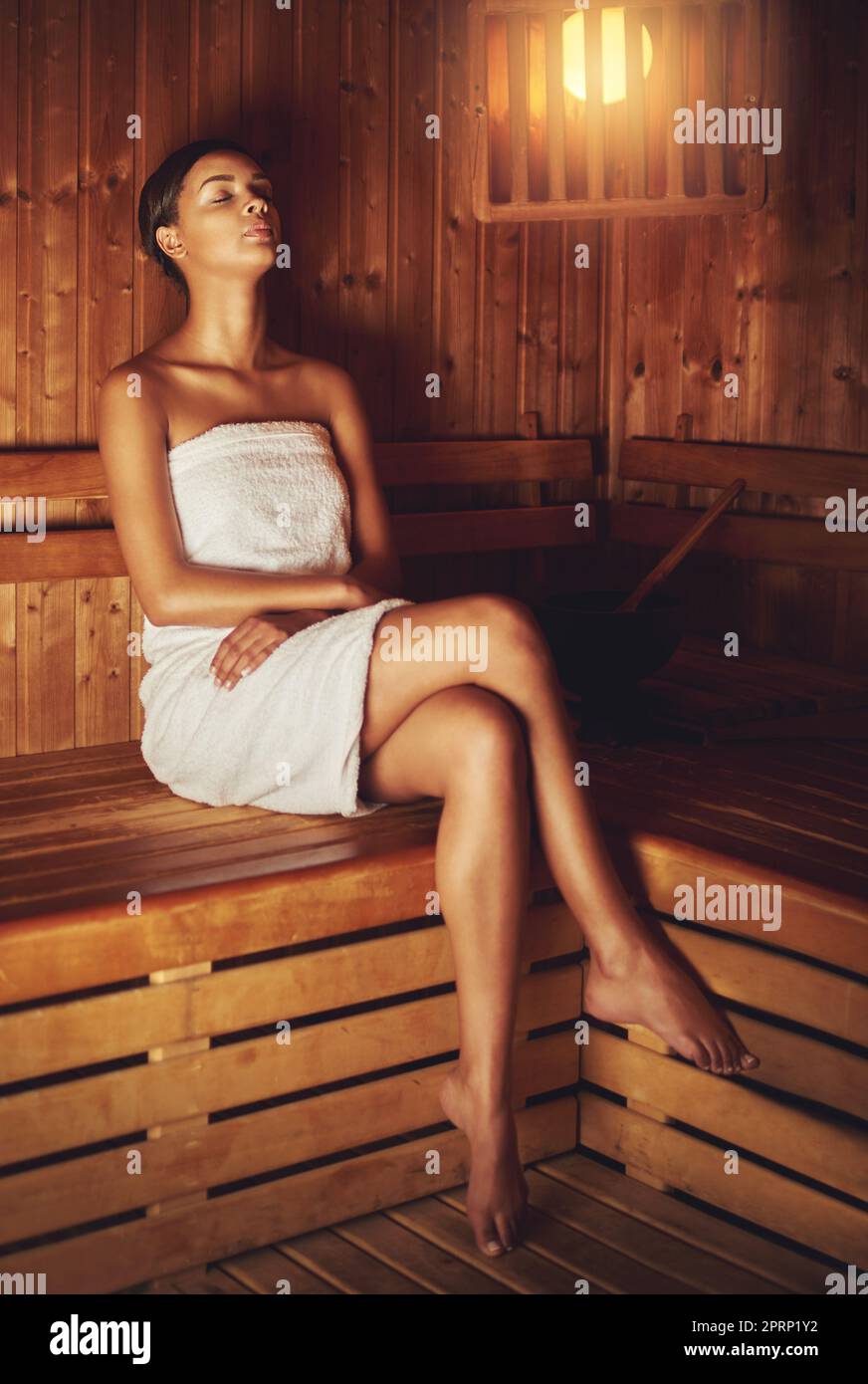 Letting the sauna relax and pamper her. Full length shot of a young woman relaxing in the sauna at a spa. Stock Photo