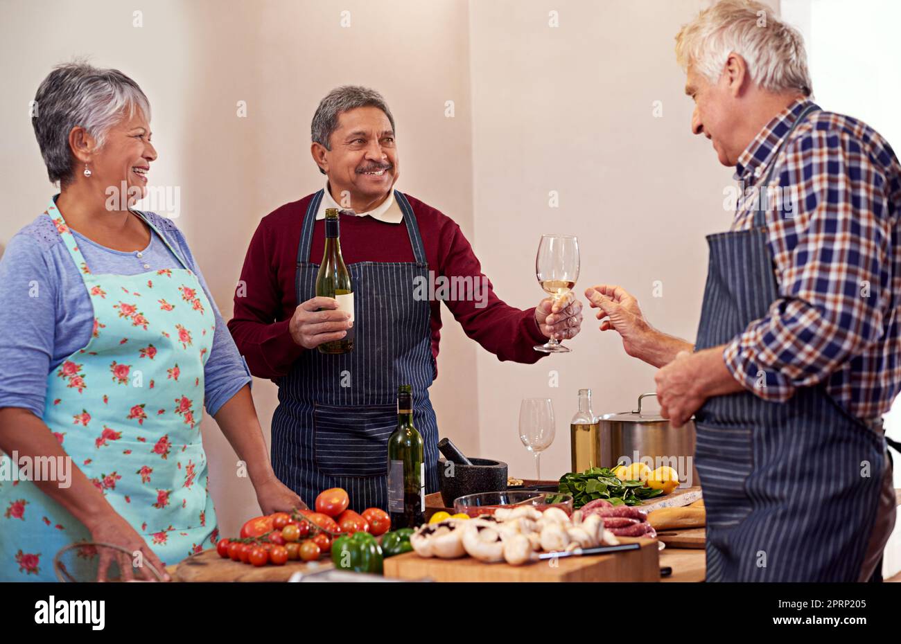 Heres to a fine meal. a group of seniors having a good time cooking together. Stock Photo