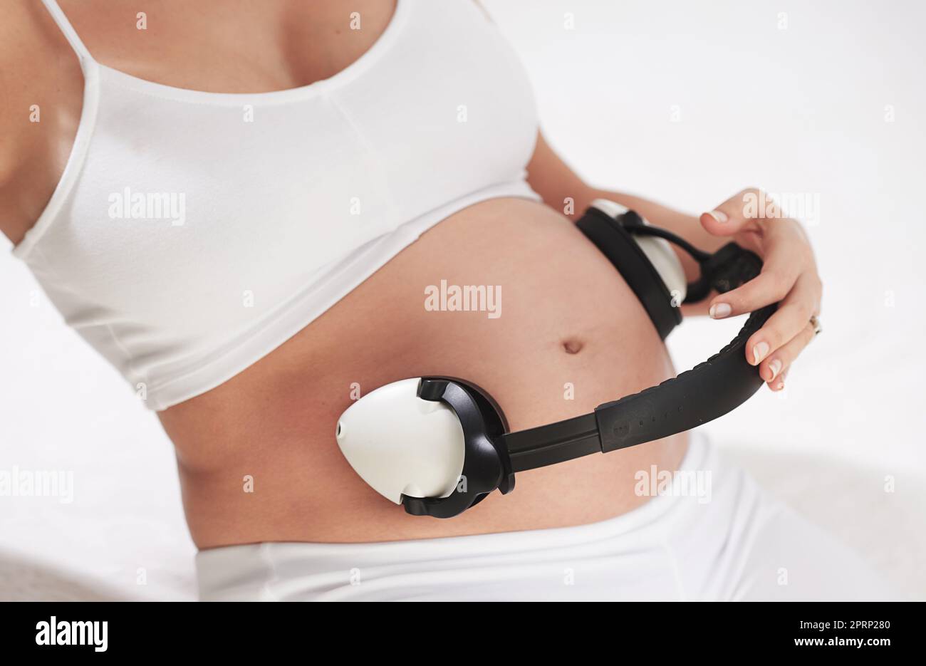 Soothing tunes for a growing tummy. a pregnant woman holding headphones around her belly. Stock Photo
