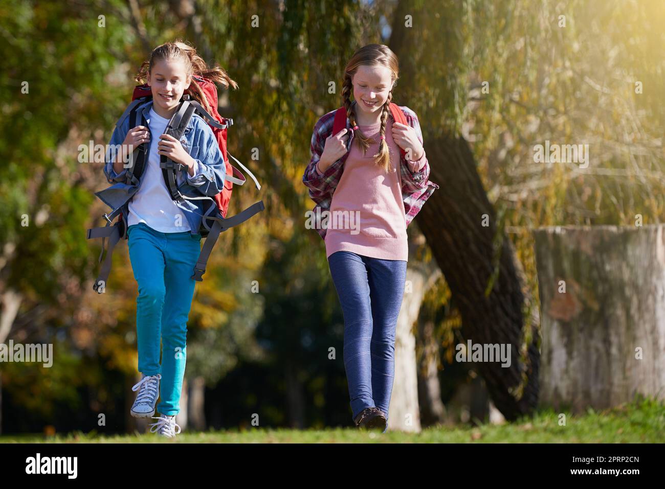 And so the adventure begins...two young girls wearing backpacks walking together in nature. Stock Photo