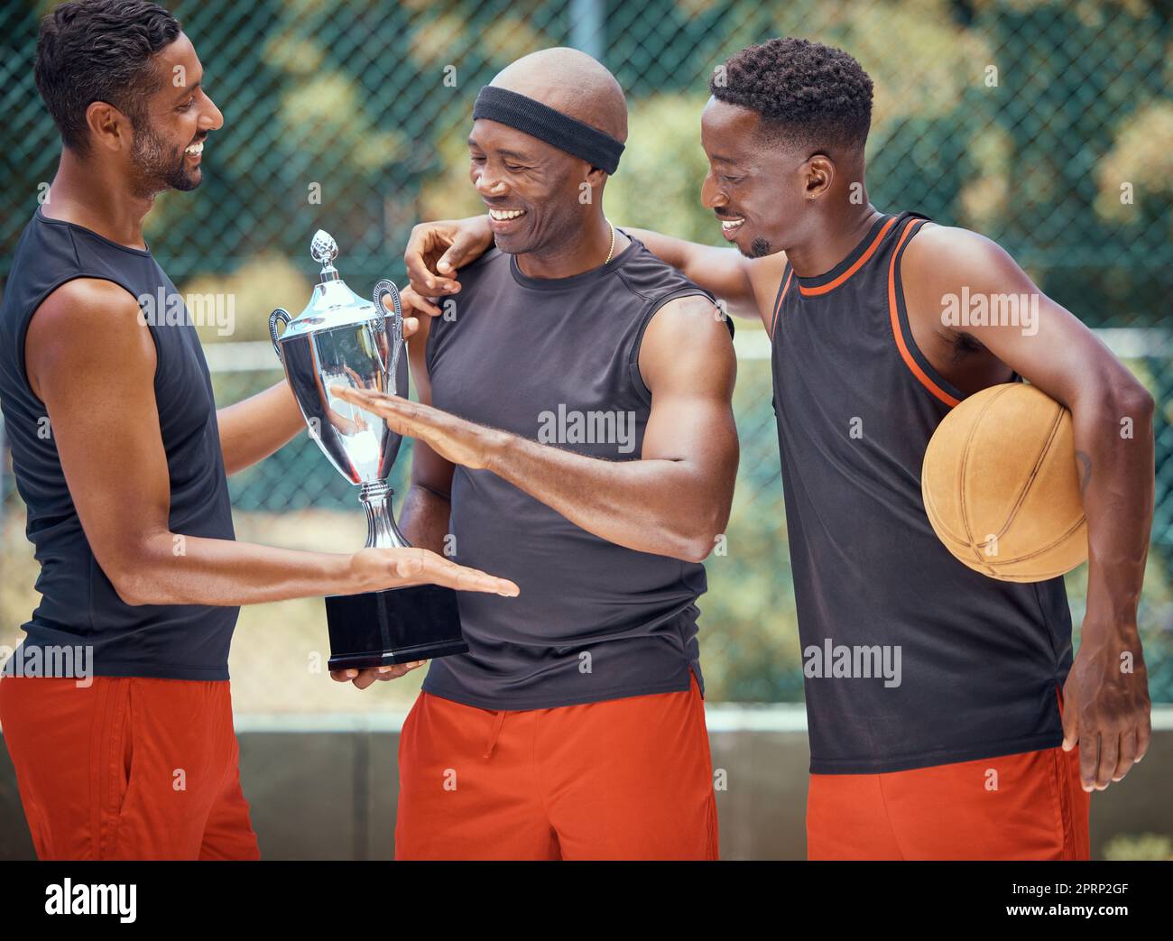 Award, success and basketball athletes with a trophy as a reward or prize after winning a competitive sports game. Challenge, fitness and happy African winners in celebration after mens championship Stock Photo