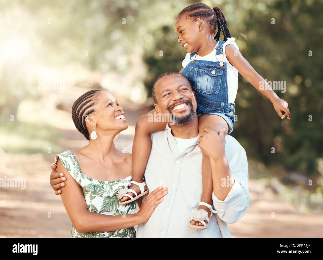 Family, love and children with a happy mother, father and daughter outside in a park during summer. Mature man and woman bonding and spending time with their cute little girl outdoors in nature Stock Photo