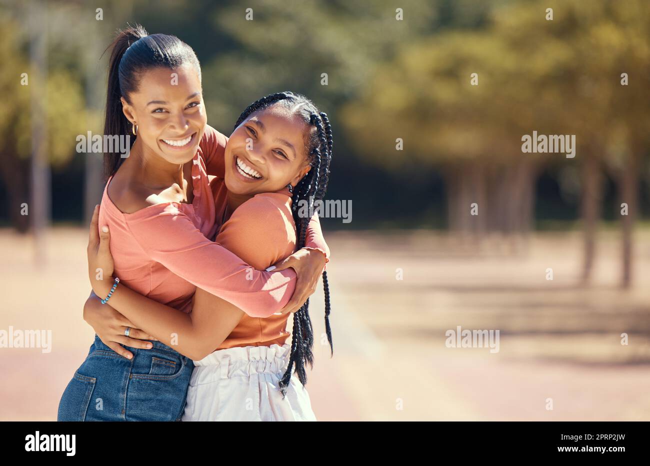 Portrait of happy friends hugging and smile outside in the park. Happy african american females embracing each other, spending the day together in the forest, enjoying a fun time during summer Stock Photo