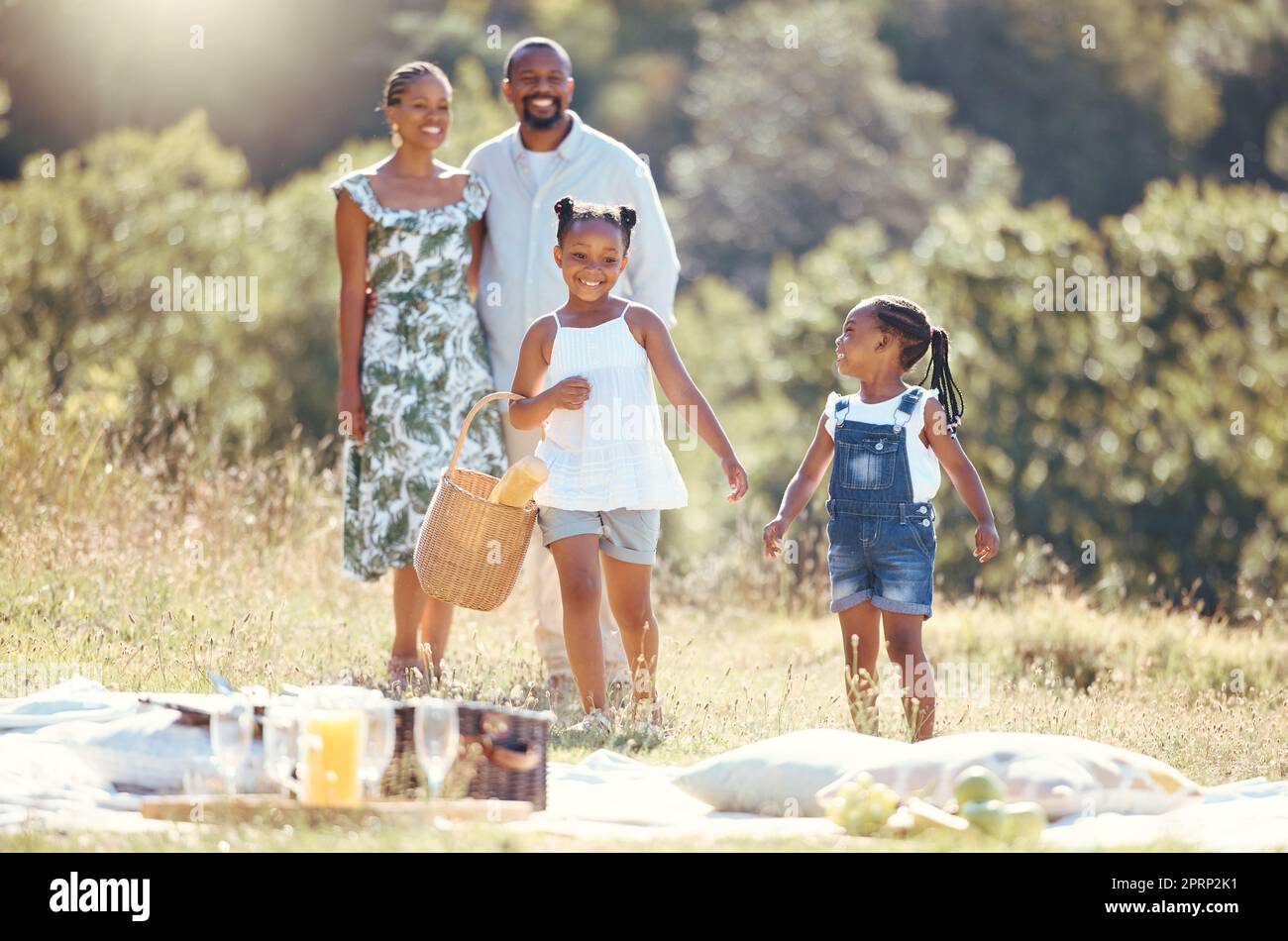 Black family, summer picnic and children bond with parents on break in remote countryside park field. Smile, happy and love mother, father or playful and fun girls in nature outing with man and woman Stock Photo