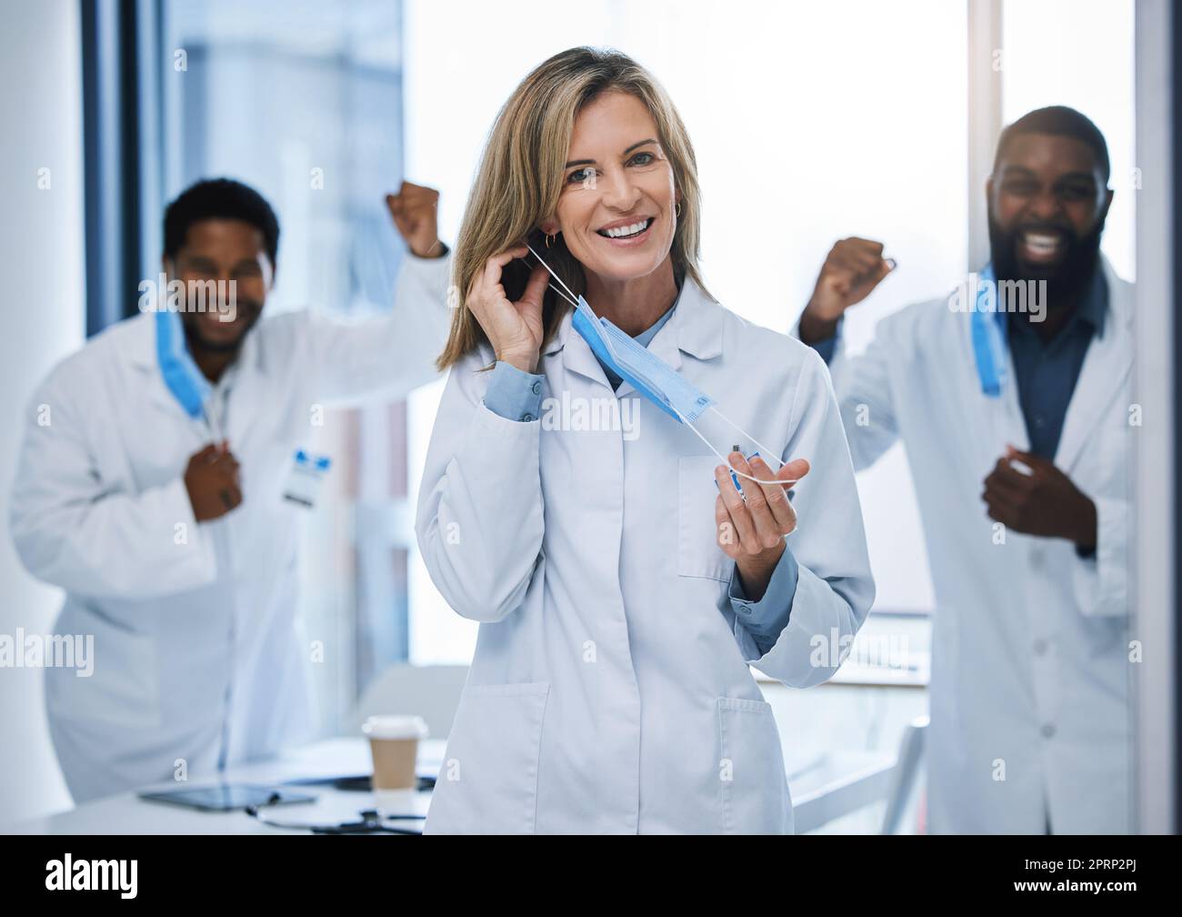 Doctors celebrate removing covid face mask at end of pandemic, celebration of virus done and success in medical hospital. Face portrait of healthcare workers happy after surgery and coronavirus Stock Photo