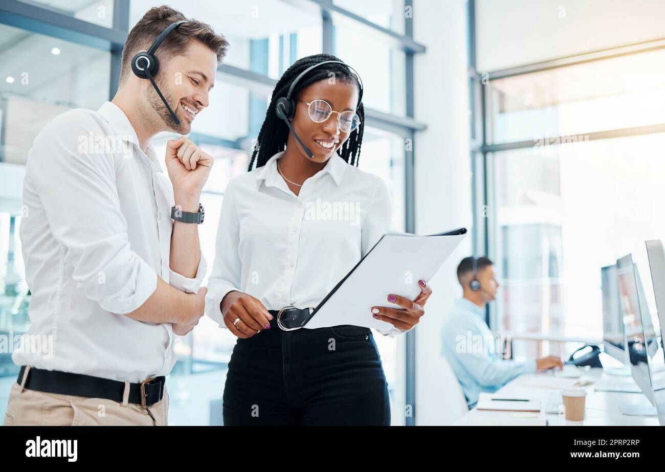 Call center, telemarketing and about us CRM consultants reading faq and qa training manual in a modern office. Collaboration, teamwork and diversity with man and woman at a customer support agency Stock Photo