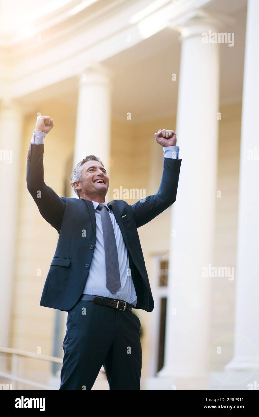 I did it. a businessman standing with his arms raised outside. Stock Photo