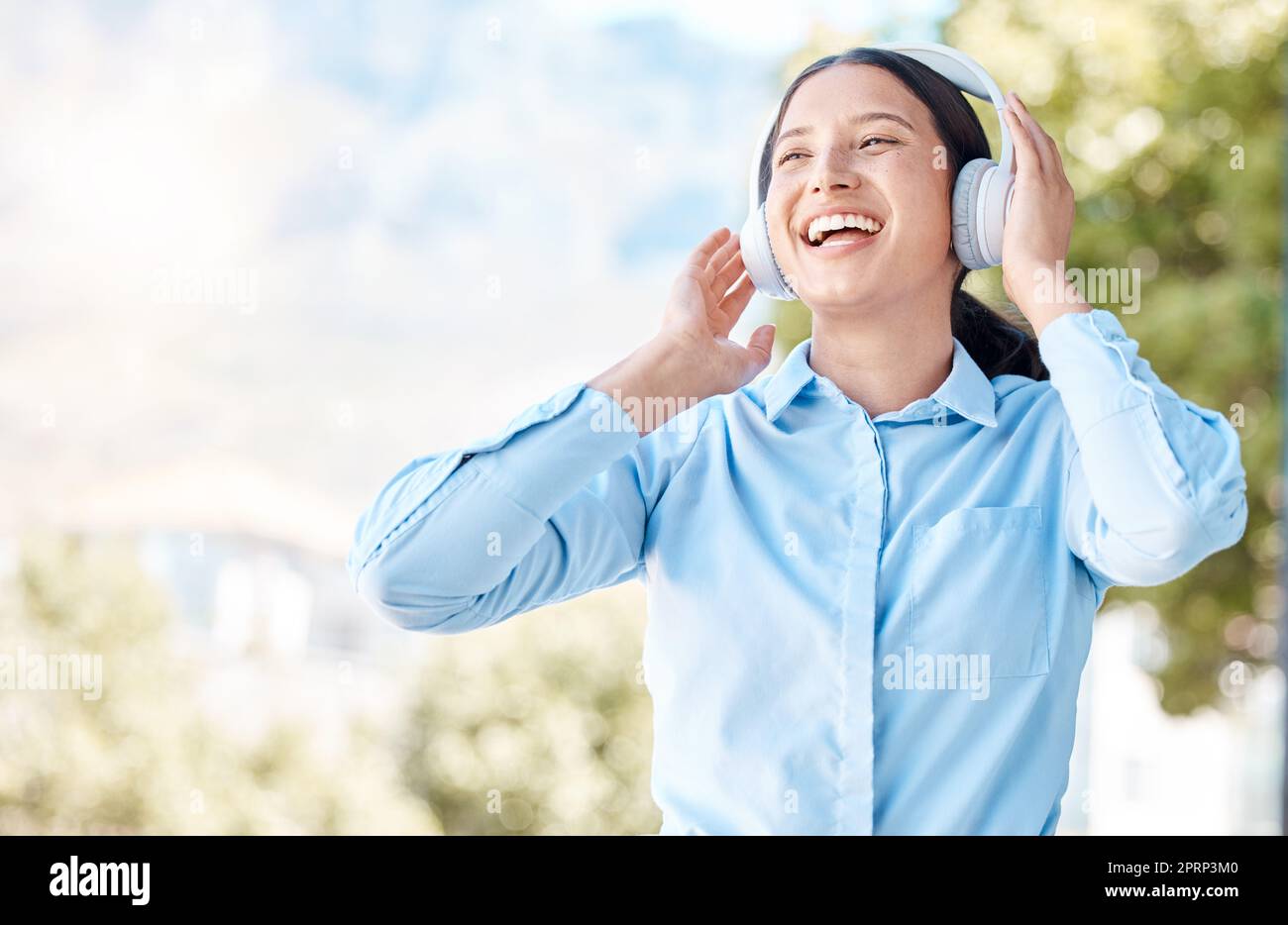 Woman with headphones happy listening to music on mp3 audio streaming song app singing to popular singer artist. Girl or young person smile, happiness and dancing to good internet joy and fun radio Stock Photo