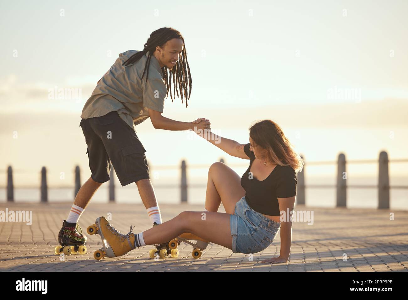 Help, falling and couple roller skating and holding hands at the beach