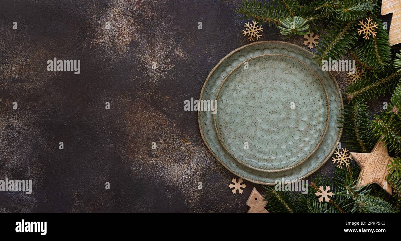 Festive table setting with fir tree branches and Rustic Christmas decorations on dark table top view Stock Photo