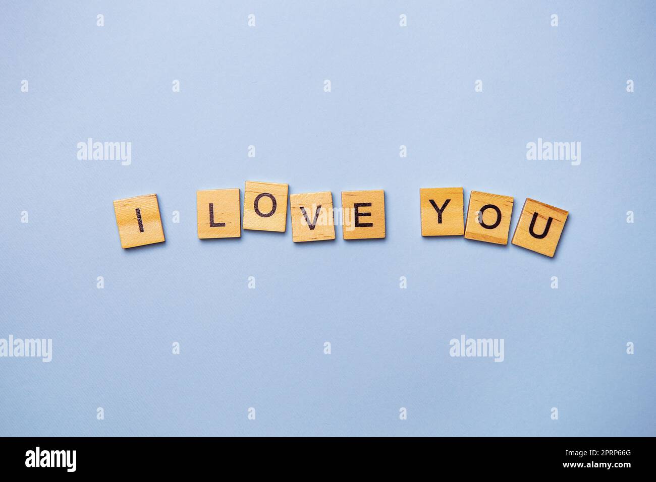 Inscription I love you in wooden square letters on a light blue background. Ready postcard, banner, place for an inscription. Stock Photo