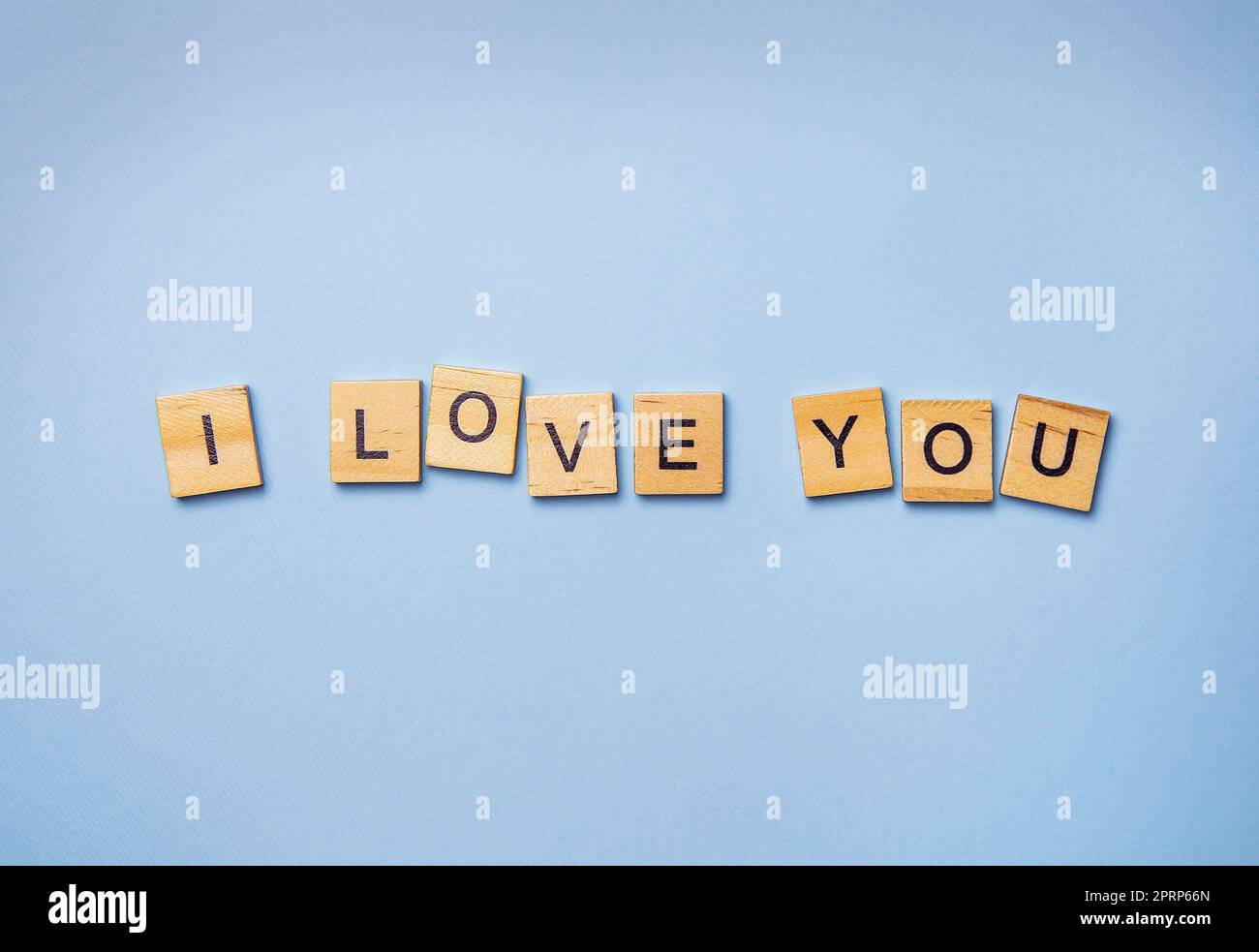 Inscription I love you in wooden square letters on a light blue background. Ready postcard, banner, place for an inscription. Stock Photo