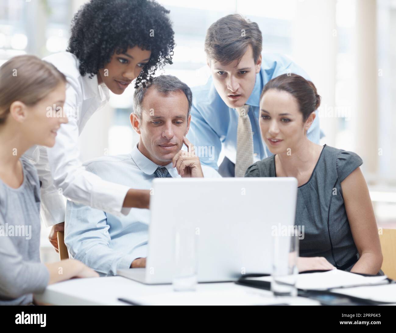 Designing the new website. A multi-ethnic group of business people sitting around a laptop during a meeting. Stock Photo