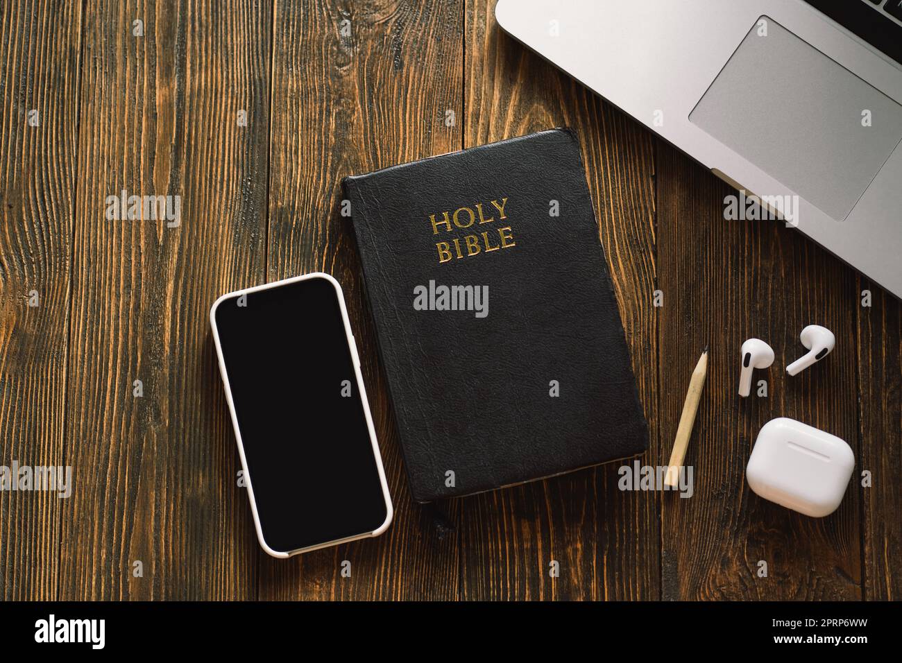 Church online Sunday new normal concept. Bible, cell phone and earbuds on a wood background. Stock Photo