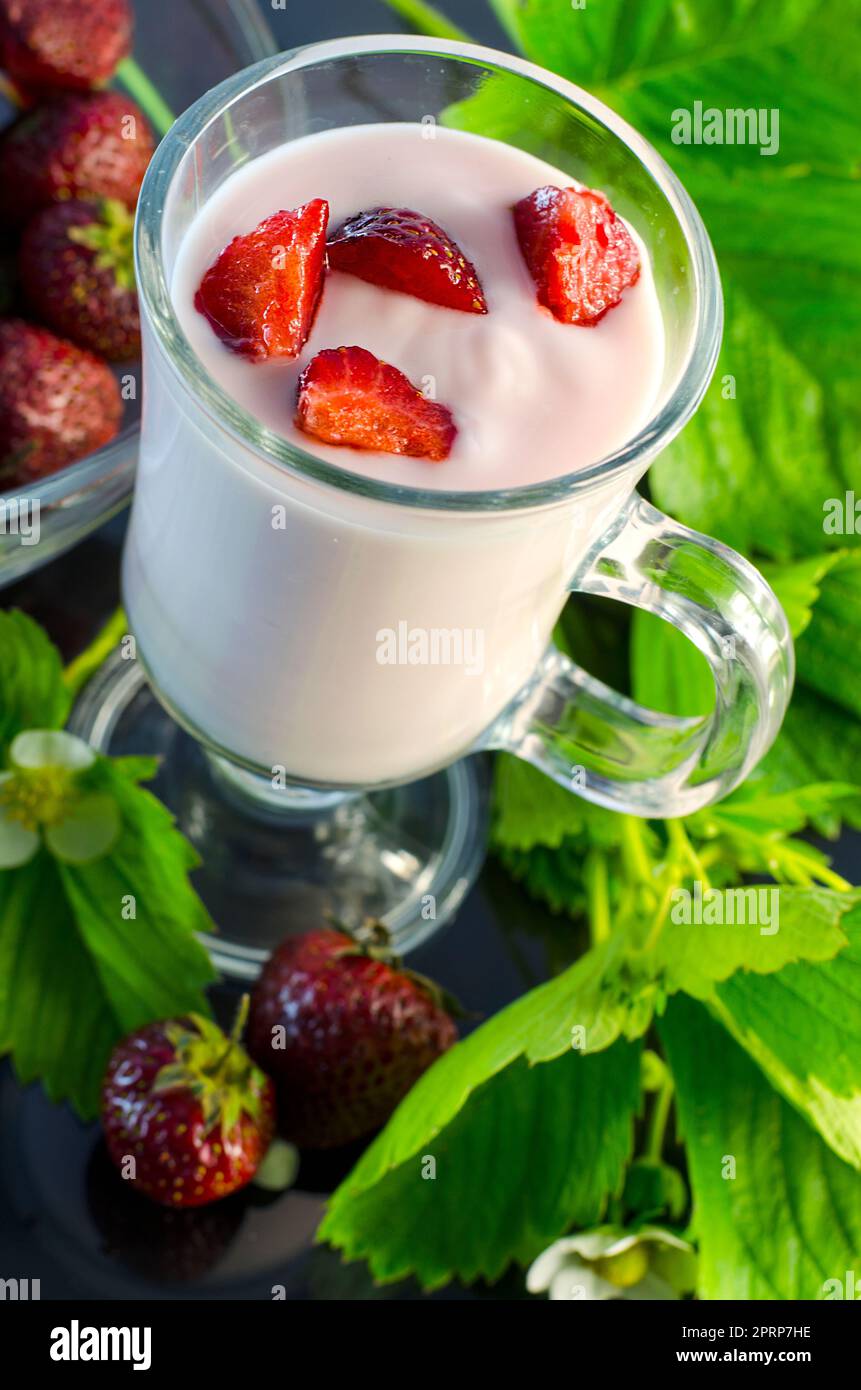 strawberry yoghurt and berries and flowers of a strawberry on a dark