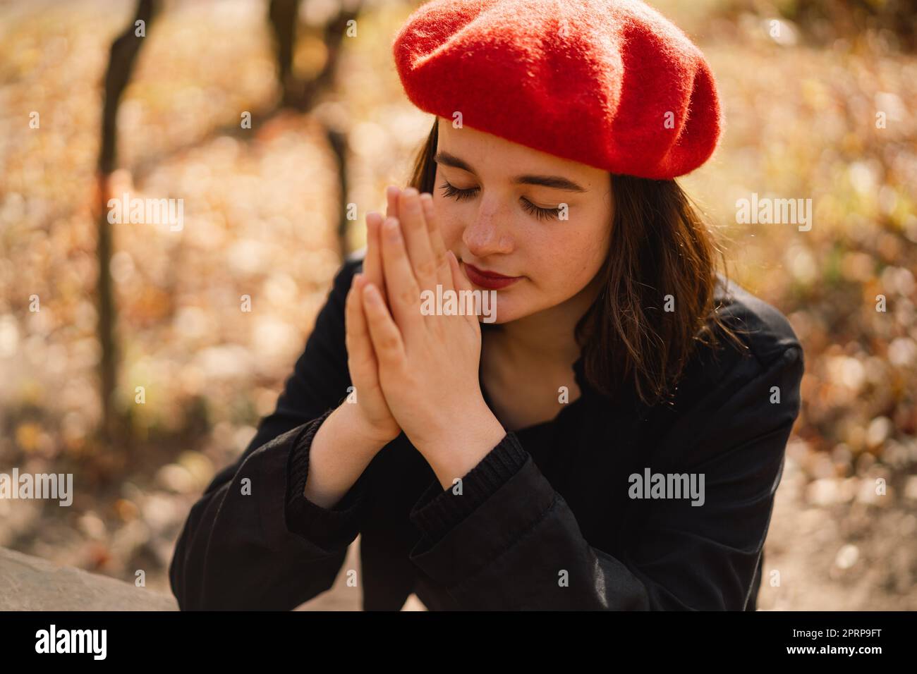 Teen girl closed her eyes and praying. Hands folded in prayer concept for faith, religion. Stock Photo