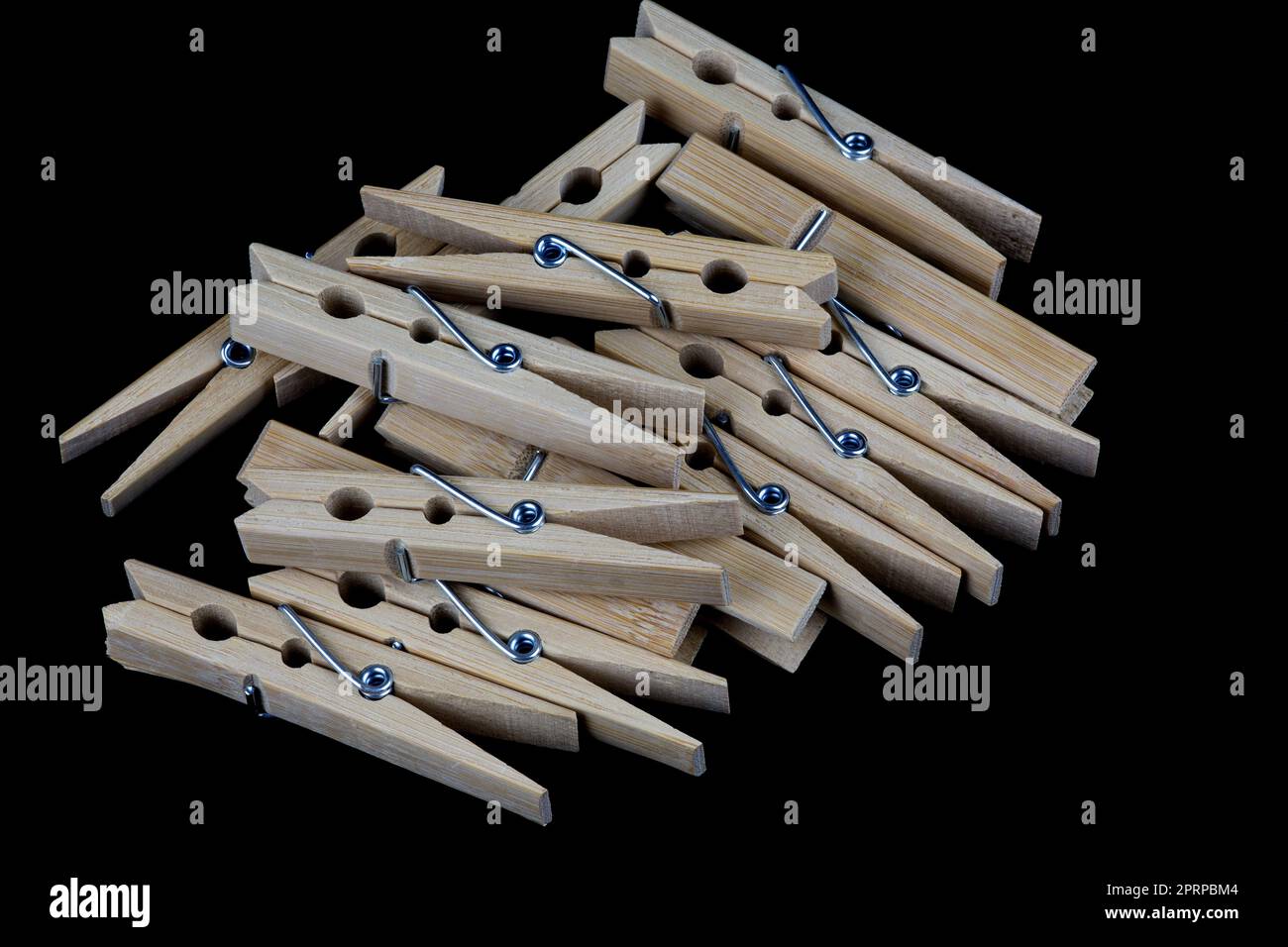 A pile of wooden clothes pegs isolated on a black background Stock Photo