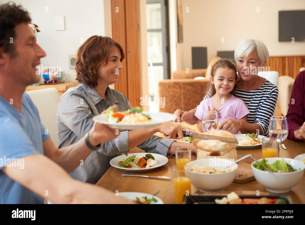 Everybody dig in. a multi generational family having a meal together around a dining table. Stock Photo