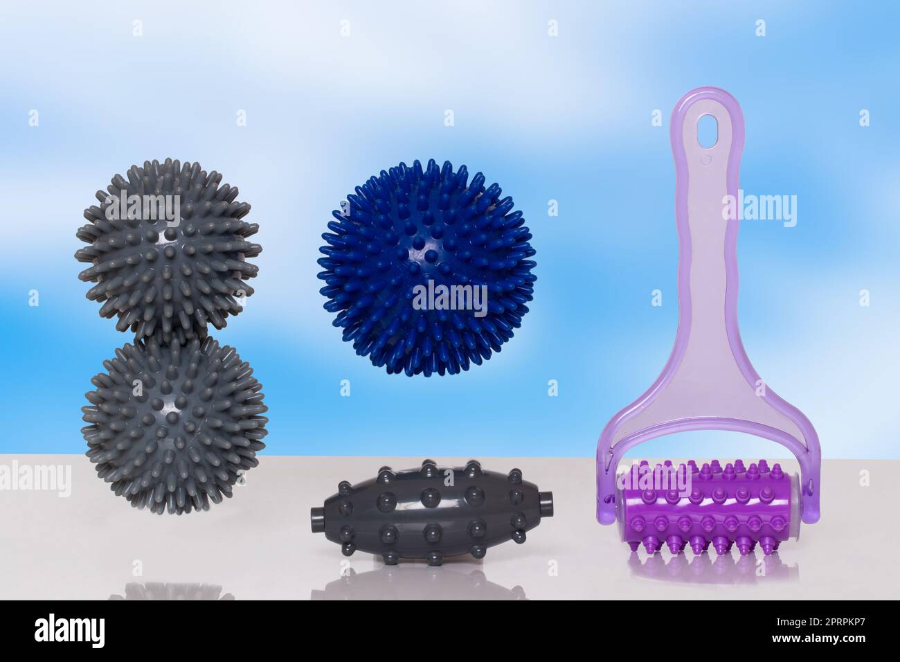 Closeup of various therapy and fitness equipment, such as massage balls or hedgehog balls and roller for health therapie on table over abstract background. Stock Photo