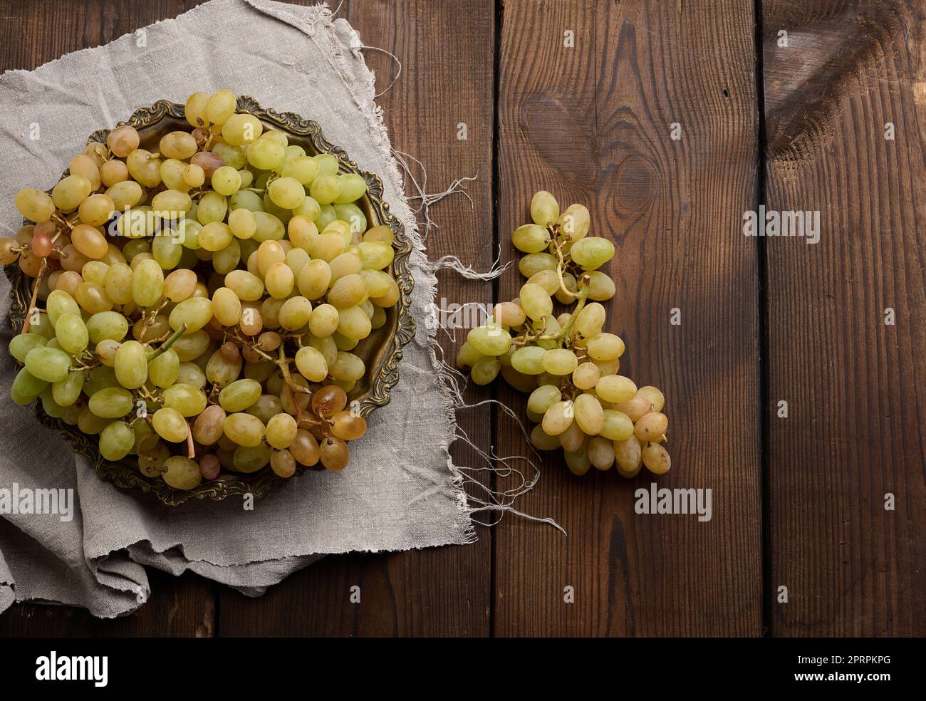 Green grapes in a wooden round plate on a black table Stock Photo