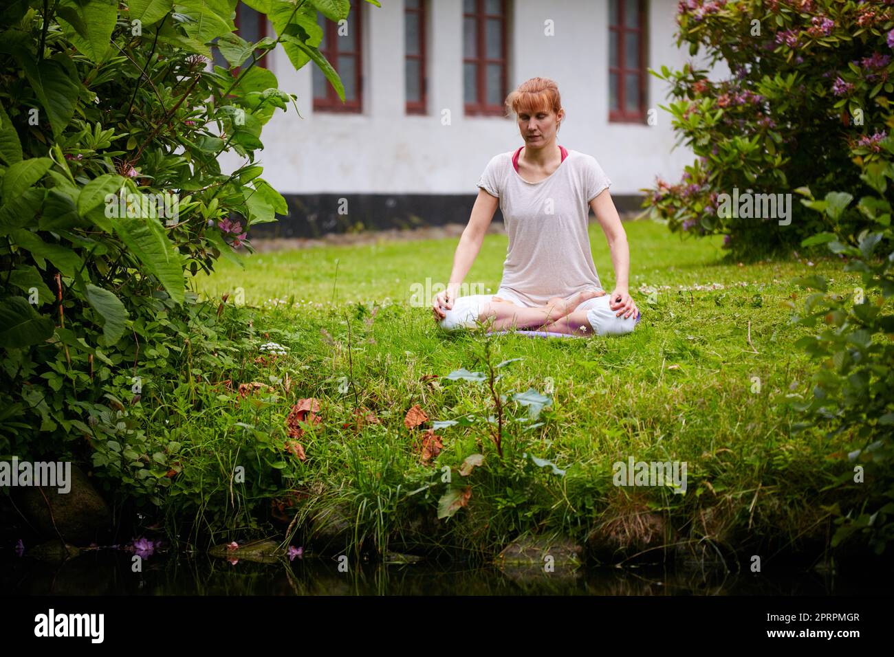 Contemplation and nature. a woman sitting in the lotus position in her backyard. Stock Photo