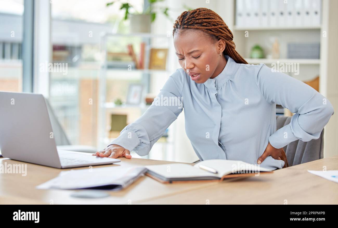 Business black woman, back pain and health stress, risk and muscle injury at modern office workplace desk job. Young african american, uncomfortable spine problem and bad sitting posture for working Stock Photo