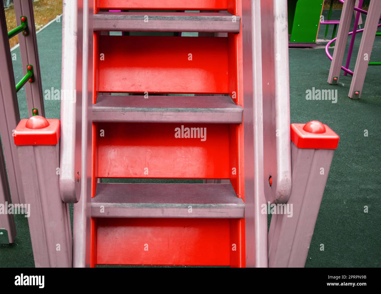 Close-up of wooden steps on an empty red staircase in an outdoor playground, a safe play area for children Stock Photo