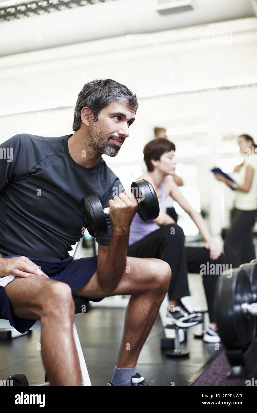 Building muscle. a handsome man working out with weights in the gym. Stock Photo