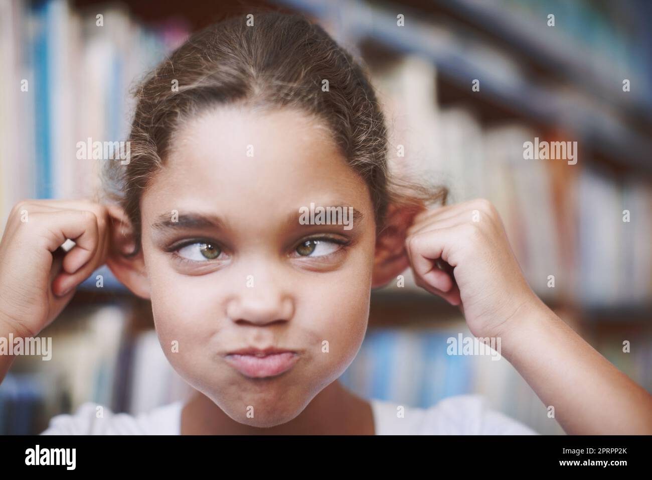 Shes the class clown. A cute young girl pulling her ears and making a