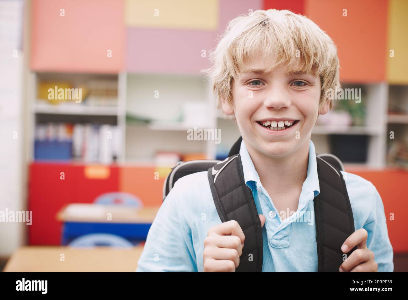 Hes excited about learning. A cute young boy wearing a backpack and