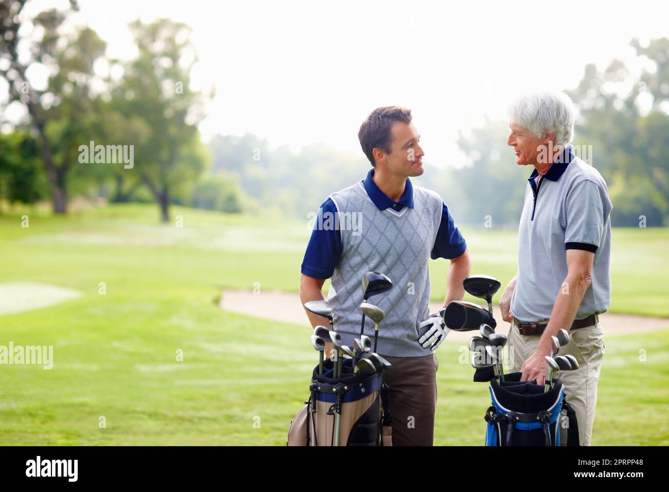 Two golfers in discussion. Father and son standing on golf course and discussing with each other. Stock Photo