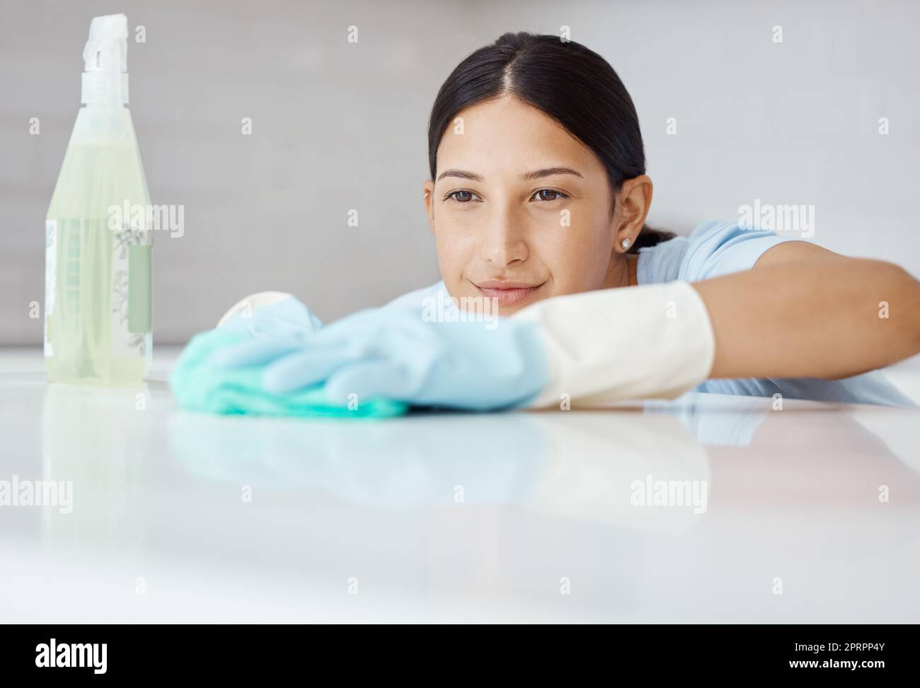 Cleaning, disinfect and housework with woman washing kitchen table with spray product to sanitize, clean and for hygiene. Housewife, cleaner or housekeeper with sanitary detergent and tidy apartment Stock Photo