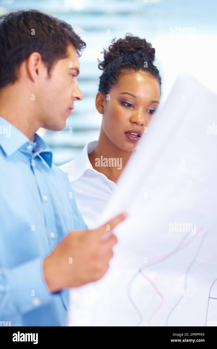 Discussion on project. Portrait of multi racial architects discussing while looking at blueprints. Stock Photo