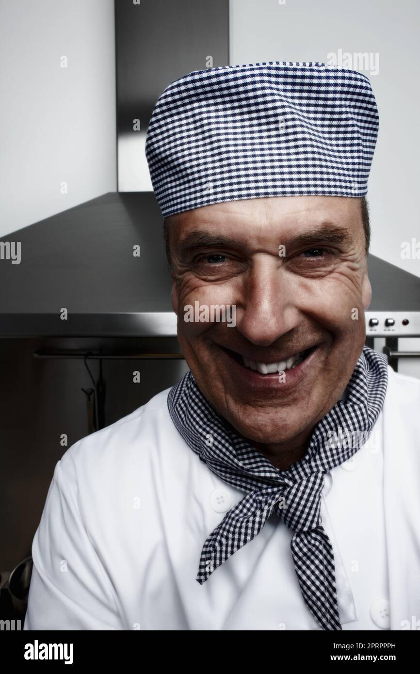 Cheerful senior chef in front of vent hood. Closeup portrait of a