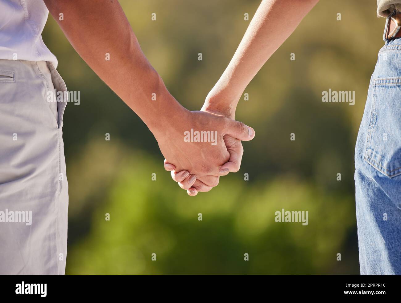 Hand, love and couple with a man and woman holding hands outside in care, trust and relationship. Closeup of a male and female walking outside together for romance and affection with trust outdoors Stock Photo