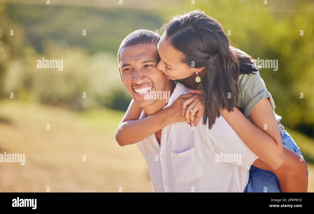 Love, date and outdoor couple in park playing on holiday, vacation or healthy lifestyle with green trees, bokeh and summer sun. Happy, wellness black people piggyback ride together or nature hiking Stock Photo