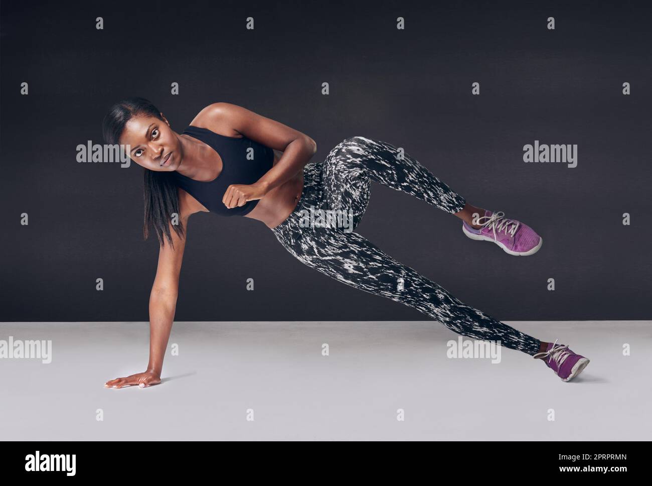 Young woman doing push-ups on a dark background. Studio shot